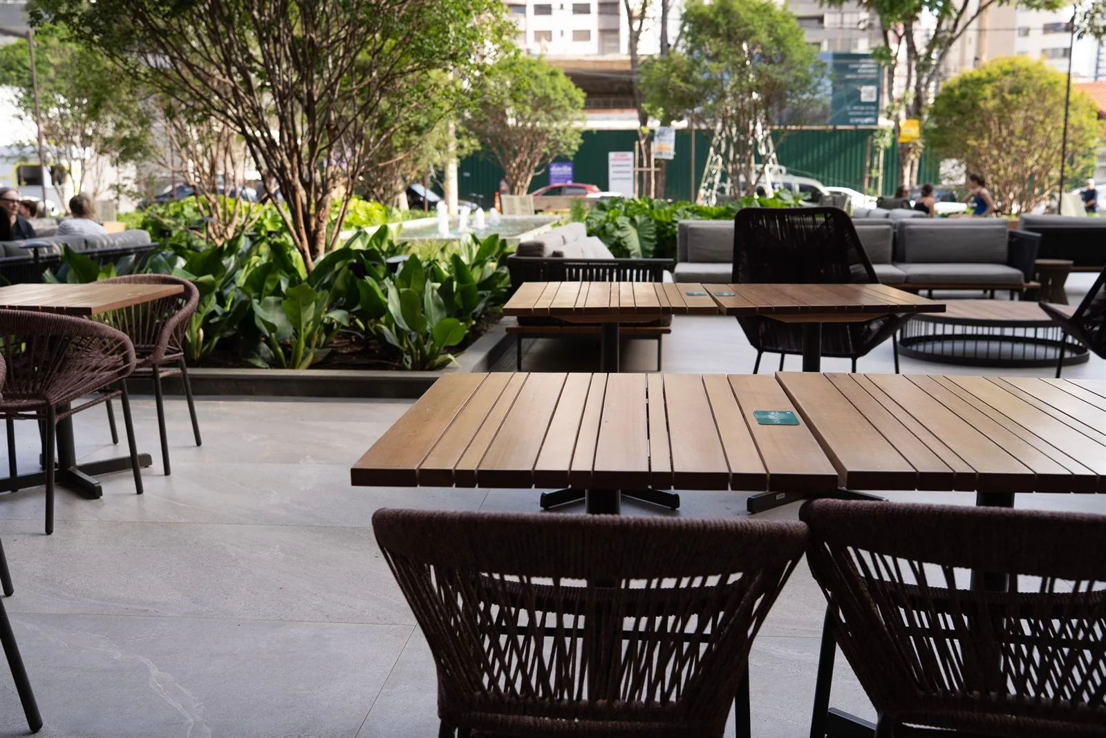 Varanda com mesas externas e jardim ao fundo